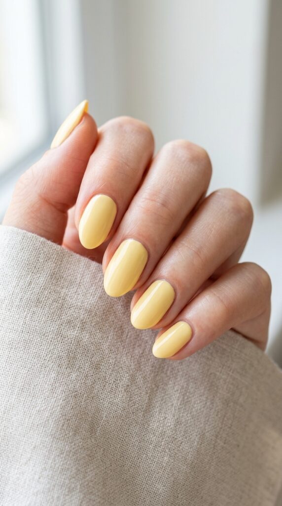 Butter yellow neutral nails with a soft pastel glossy finish, creating a fresh, clean, and elegant minimalist manicure look