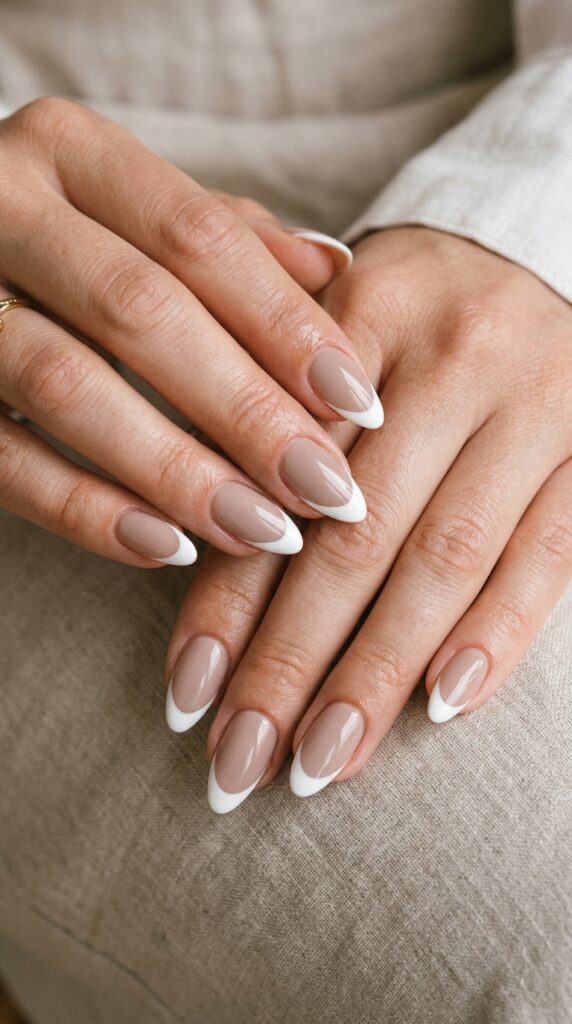 Hands with classic French manicure featuring soft nude base color and crisp white tips showing timeless elegant design perfect for professional minimalist summer nails






