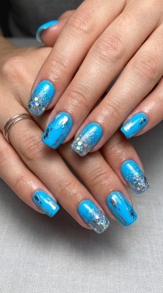 Hands with electric blue neon nail polish featuring metallic silver or holographic accent details creating glamorous dimensional shimmer effect for bold luxurious summer manicure






