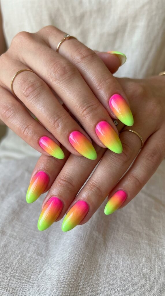 Hands with electric pink to lime green gradient nail design flowing through orange and yellow creating sunset-inspired multi-neon progression for vibrant bold summer manicure






