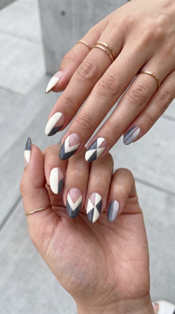Hands with geometric negative space pattern featuring chevrons, triangles, and angular shapes combining polished areas with intentional bare nail sections for sophisticated architectural minimalist summer design






