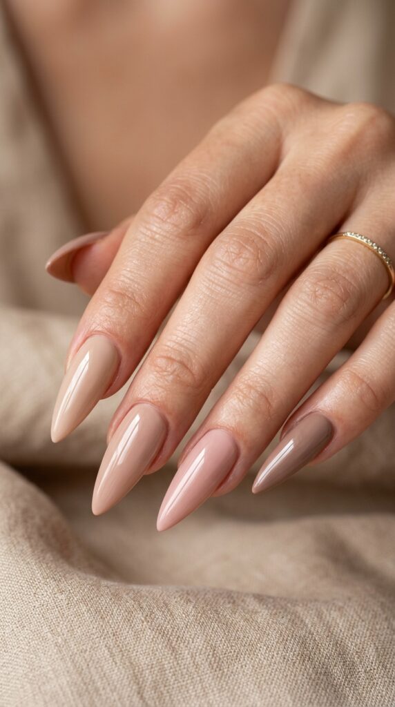 Glossy nude stiletto nails with a sleek pointed shape, soft natural tones, and a shiny elegant finish