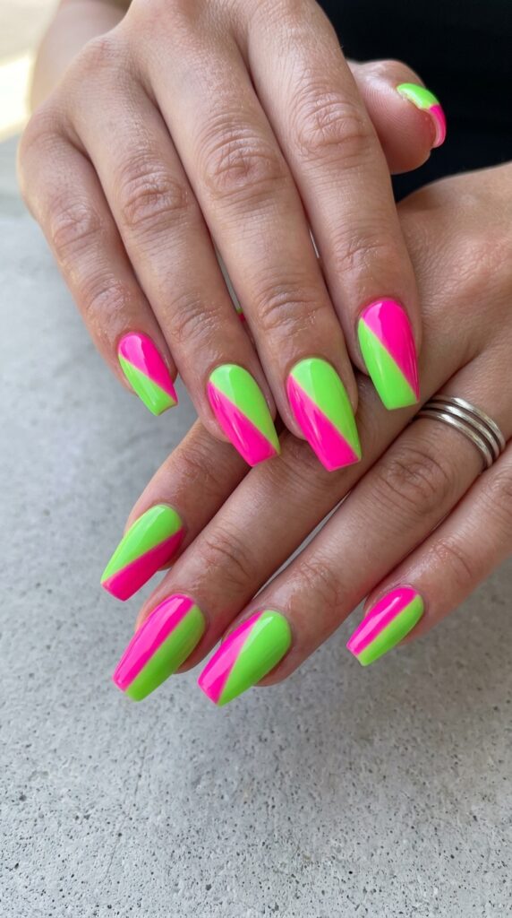 Hands with diagonal split nail design featuring hot pink and lime green neon divided from corner to corner creating striking geometric contrast for bold energetic summer manicure






