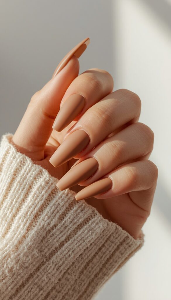 Close-up of coffin nails in matte neutral tones, soft velvety finish, and a clean minimalist aesthetic