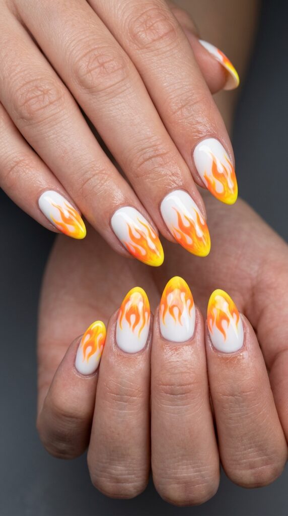 Hands with neon orange to yellow gradient flame nail design creating realistic fiery artwork across nails for dramatic bold artistic summer manicure






