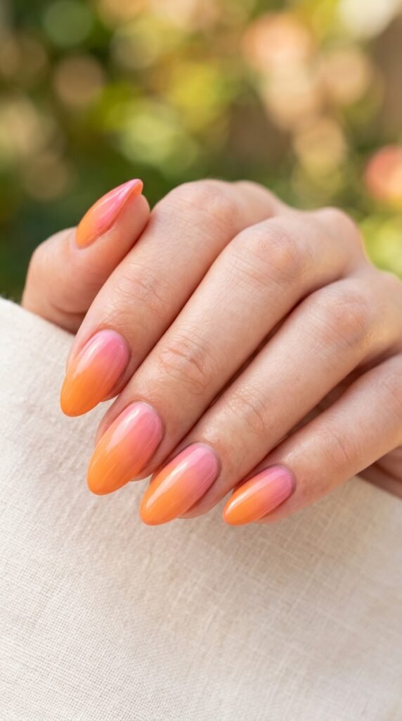 Sunset orange to pink gradient nails with a smooth ombre blend and glossy finish, creating a vibrant, warm, and trendy summer manicure look