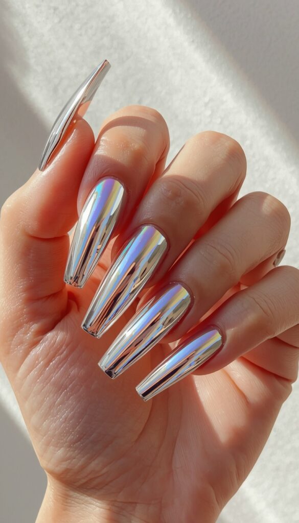 Close-up of acrylic nails with chrome metallic finish, reflective shine, and a bold modern aesthetic