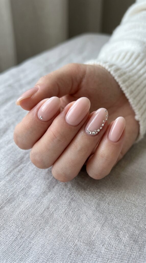 Nude nails with rhinestone accents creating a minimal yet glamorous manicure with a clean, elegant, and luxurious look